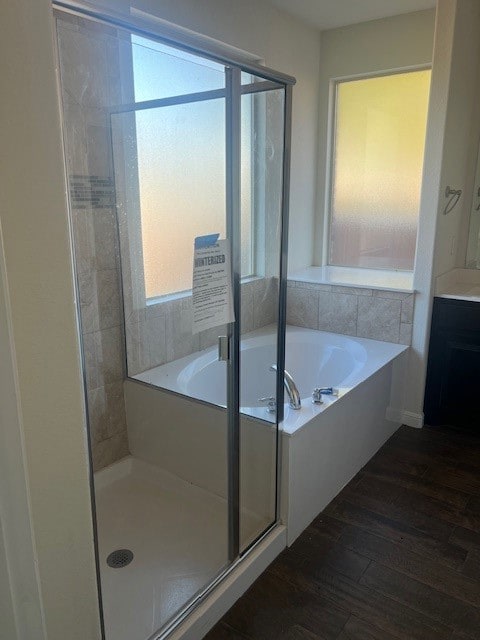 Bathroom featuring dark wood-type flooring, a bath, a shower stall, and vanity