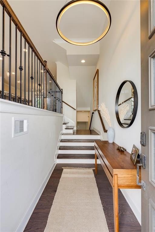 Stairway with wood finished floors, baseboards, recessed lighting, and a high ceiling
