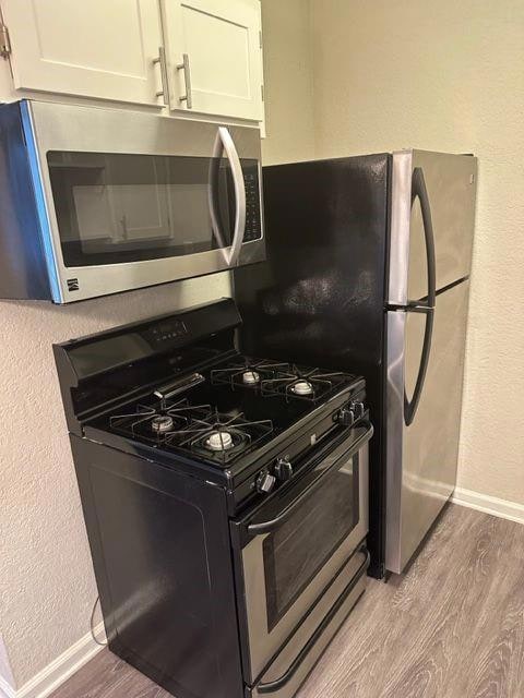 Kitchen featuring white cabinetry, stainless stee