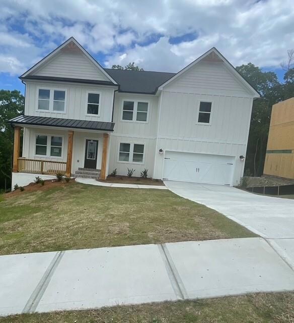 View of front of property featuring board and batten siding, an attached garage, a standing seam roof, concrete driveway, and covered porch