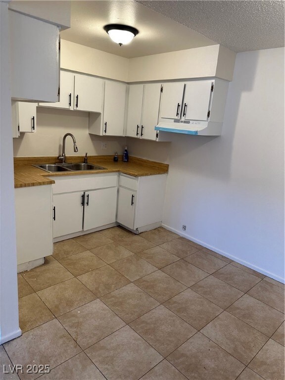 Kitchen featuring a textured ceiling, a sink, whit