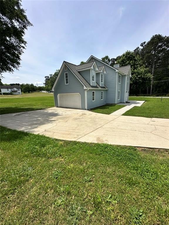 View of side of property with concrete driveway, a