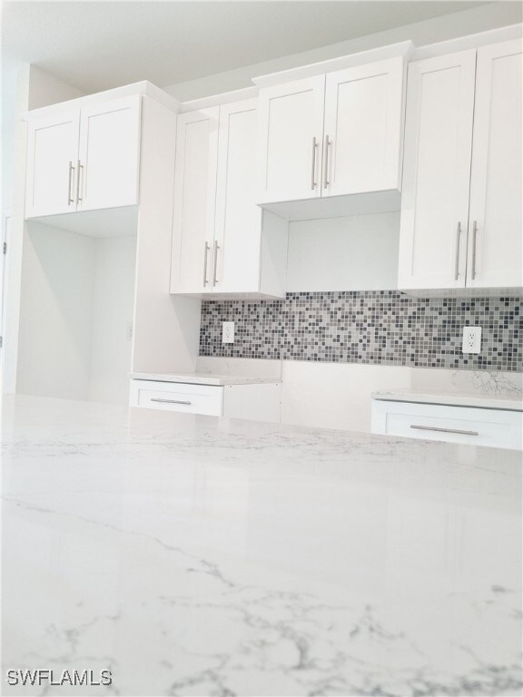 Kitchen featuring backsplash, white cabinetry, and