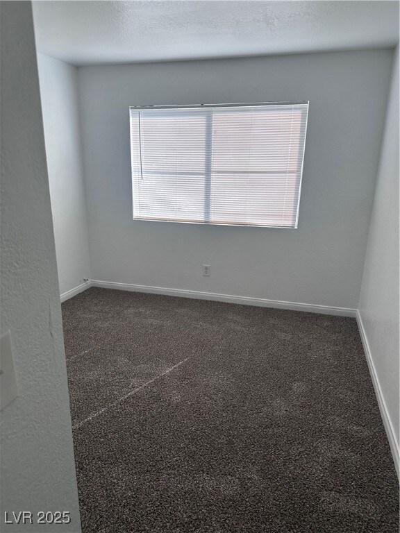Unfurnished room featuring dark colored carpet, a