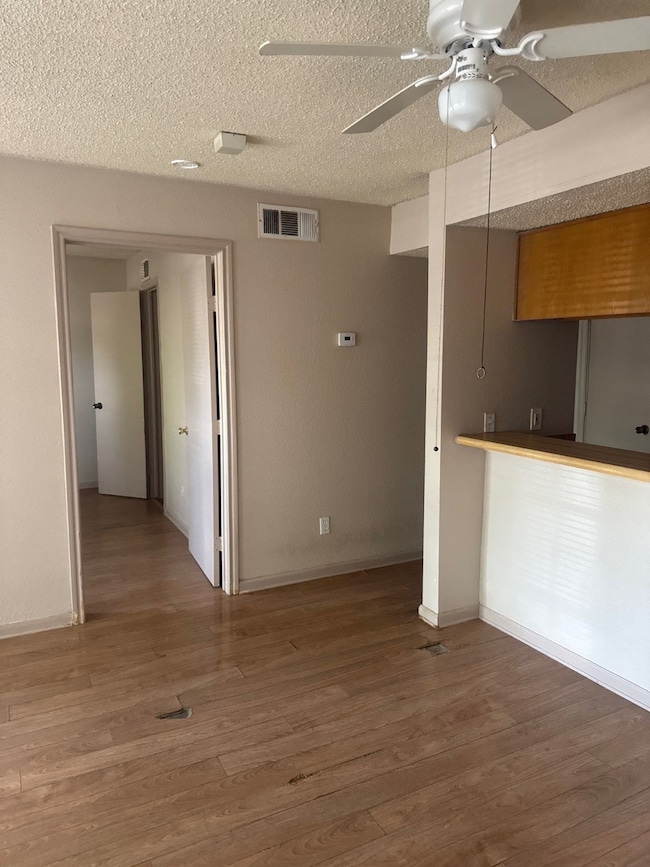 Unfurnished living room featuring wood finished floors, ceiling fan, and a textured ceiling