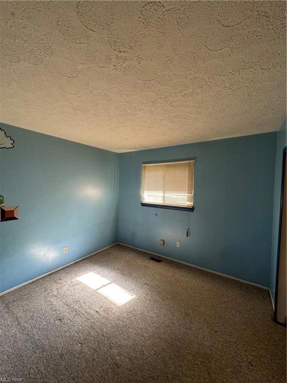 Carpeted empty room with a textured ceiling
