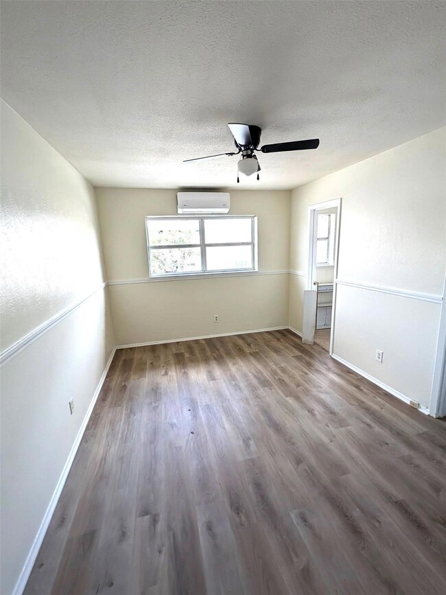 Unfurnished room featuring baseboards, an AC wall 
