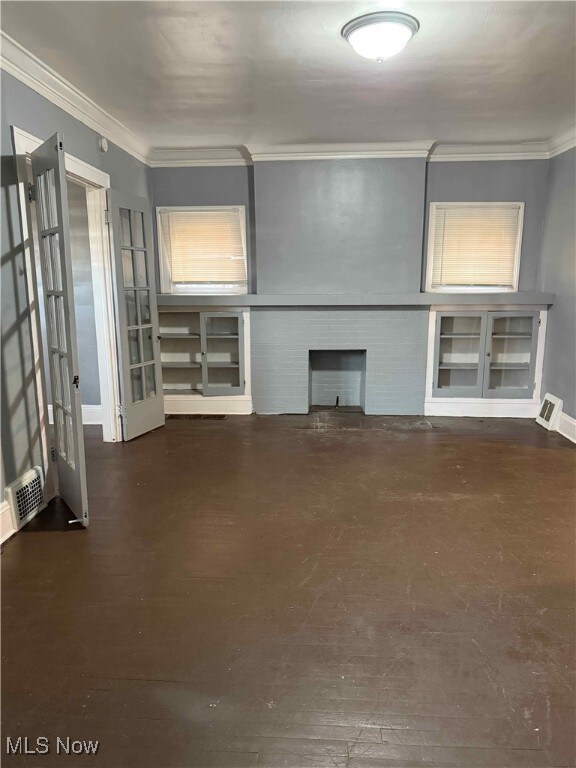 Unfurnished living room featuring ornamental molding and dark wood finished floors