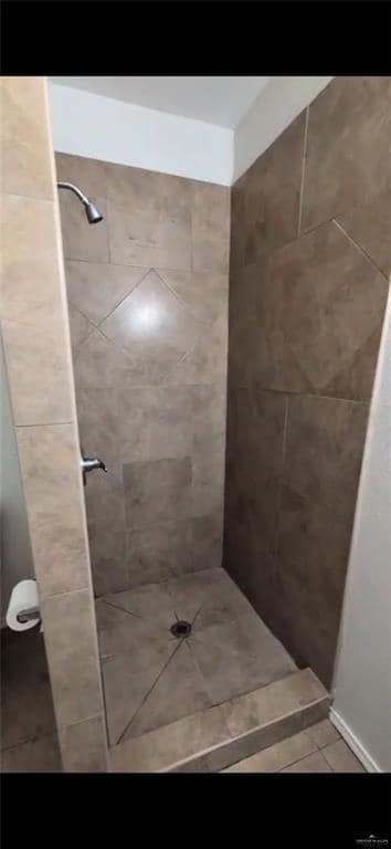 Bathroom with tiled shower and tile patterned flooring
