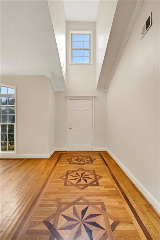 Foyer featuring baseboards, healthy amount of natural light, wood finished floors, and a high ceiling