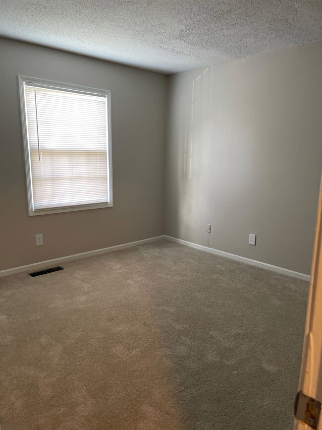 Carpeted empty room featuring a textured ceiling and baseboards
