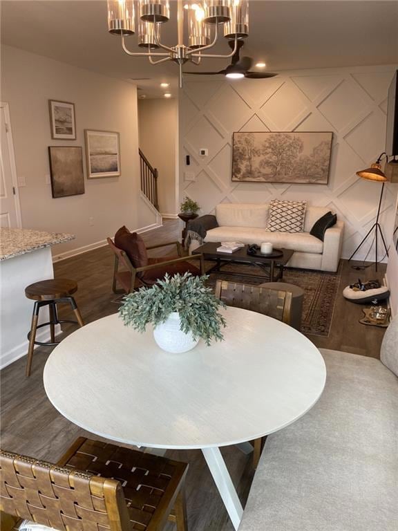 Dining area featuring a chandelier, an accent wall, recessed lighting, dark wood-style flooring, and stairs