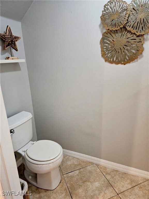Bathroom with toilet, baseboards, and tile pattern