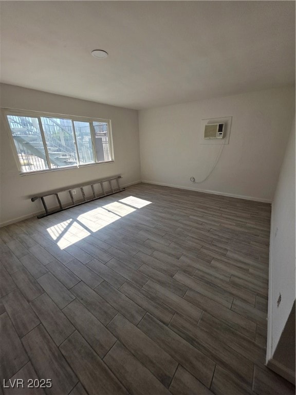 Unfurnished room with dark wood-type flooring and an AC wall unit