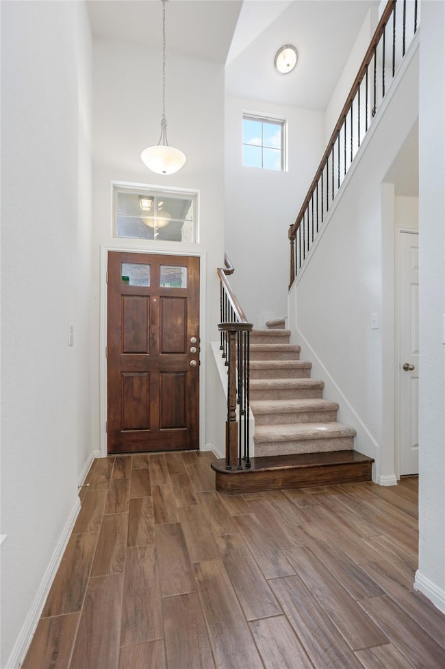 Foyer with baseboards, a towering ceiling, stairs