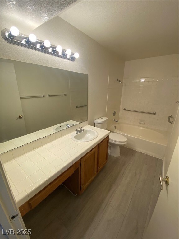 Full bathroom featuring dark wood-type flooring, vanity, and washtub / shower combination