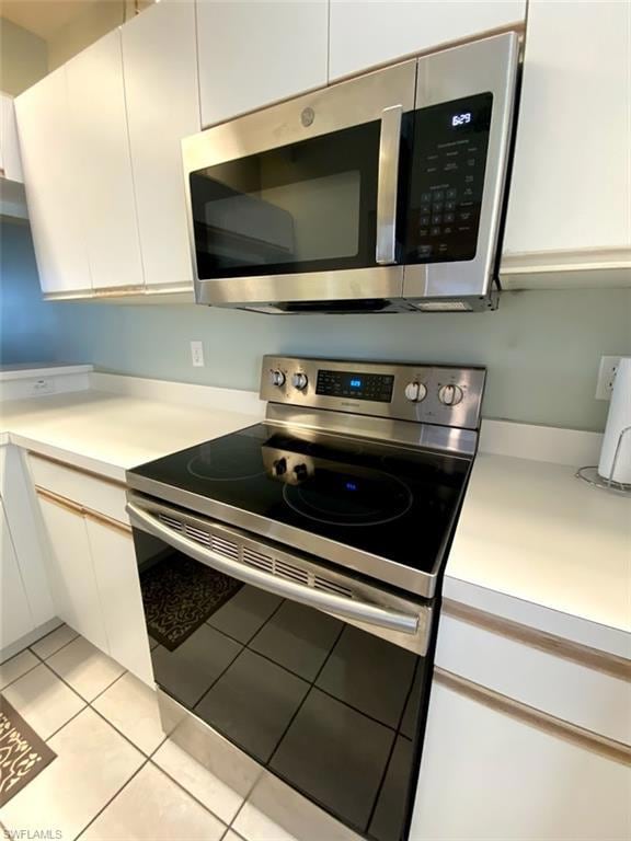 Kitchen with white cabinetry, appliances with stai