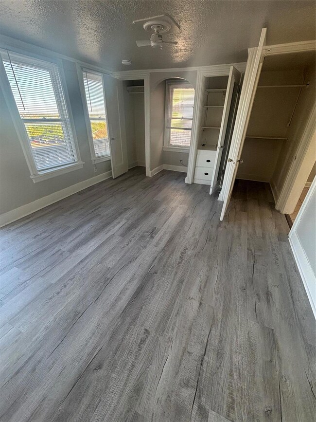 Unfurnished bedroom with a textured ceiling, multiple windows, and hardwood / wood-style flooring