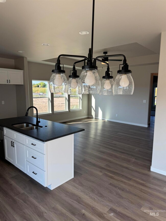 Kitchen featuring white cabinetry, dark wood-style flooring, open floor plan, a center island with sink, and recessed lighting