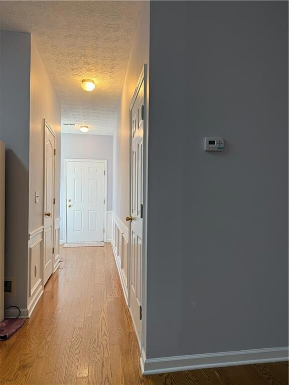Corridor with a wainscoted wall, a textured ceilin