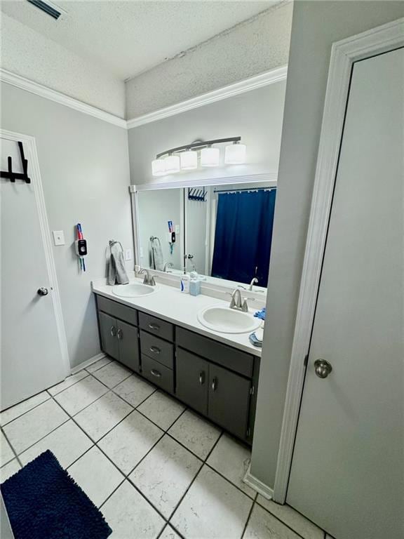 Master Bathroom featuring double vanity, a textured ceiling, light tile patterned floors, and ornamental molding