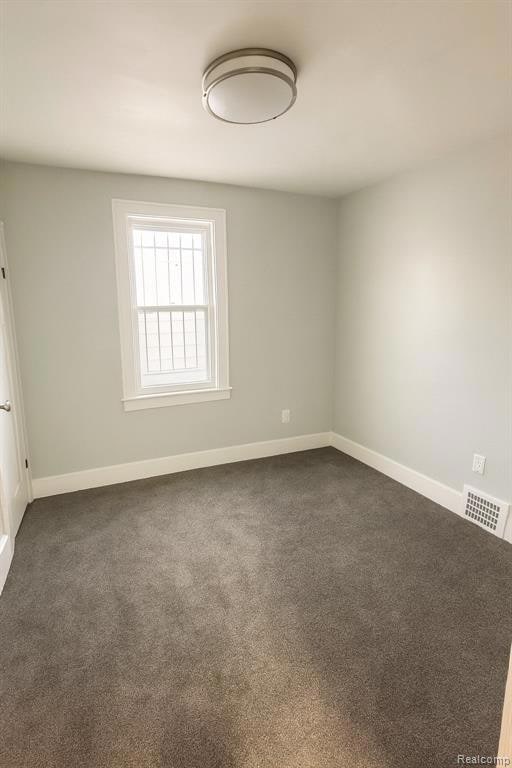 Carpeted spare room with baseboards