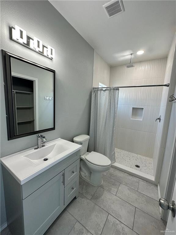 Bathroom with curtained shower, tile flooring, vanity, and toilet