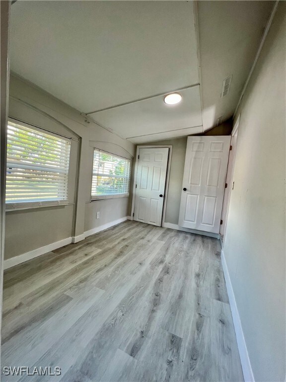 Unfurnished bedroom featuring visible vents, baseboards, and wood finished floors