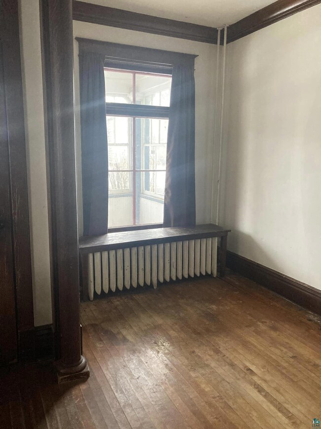 Spare room with dark wood-type flooring and orname