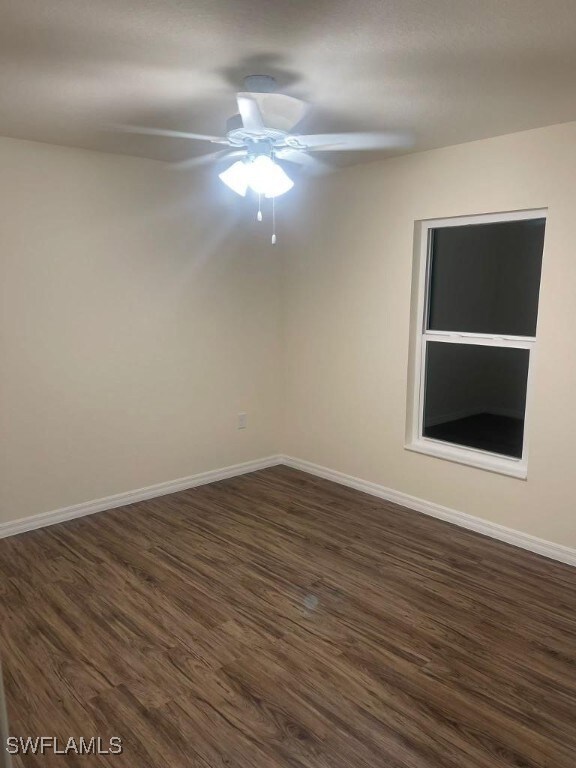 Unfurnished room with dark wood-style floors, a ce