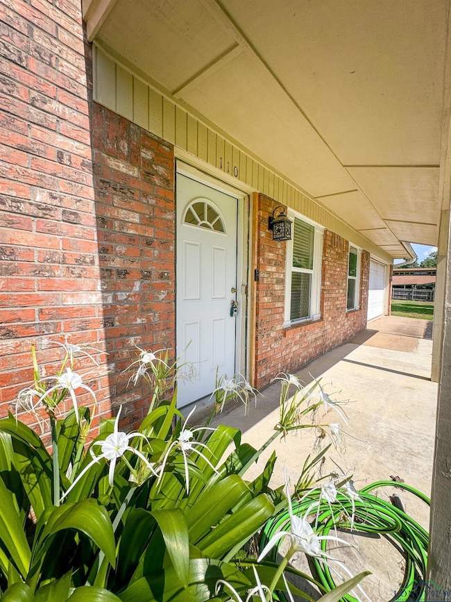 View of exterior entry featuring brick siding and covered porch
