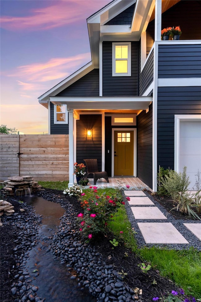Exterior entry at dusk with a balcony, fence, and
