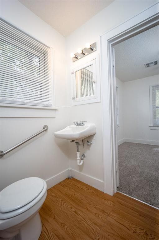 Half bath featuring toilet and light wood finished floors