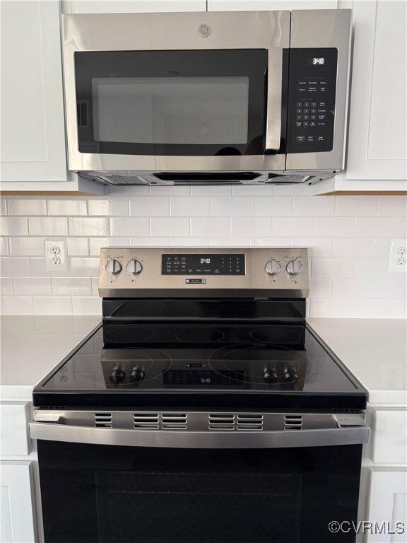 Kitchen featuring white cabinets, stainless steel appliances, and tasteful backsplash