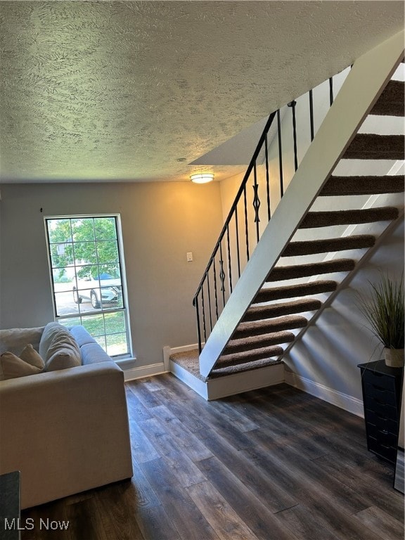 Living room featuring a textured ceiling, stairway, and dark wood-style flooring