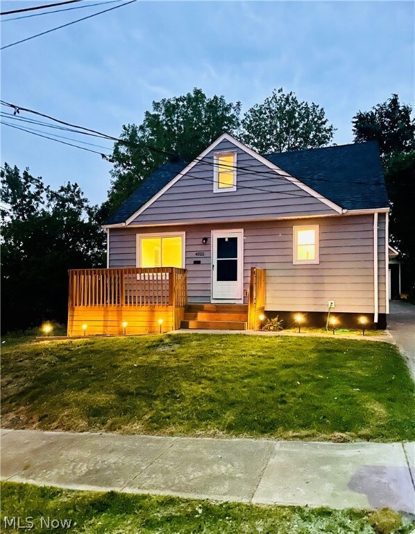 View of front of house featuring a front lawn and a wooden deck