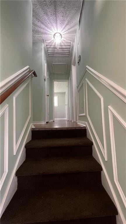 Stairway with a decorative wall and a textured ceiling