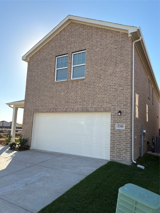 View of home's exterior featuring brick siding, a garage, and driveway