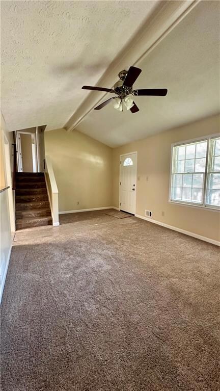 Unfurnished room featuring carpet flooring, a textured ceiling, stairs, and ceiling fan