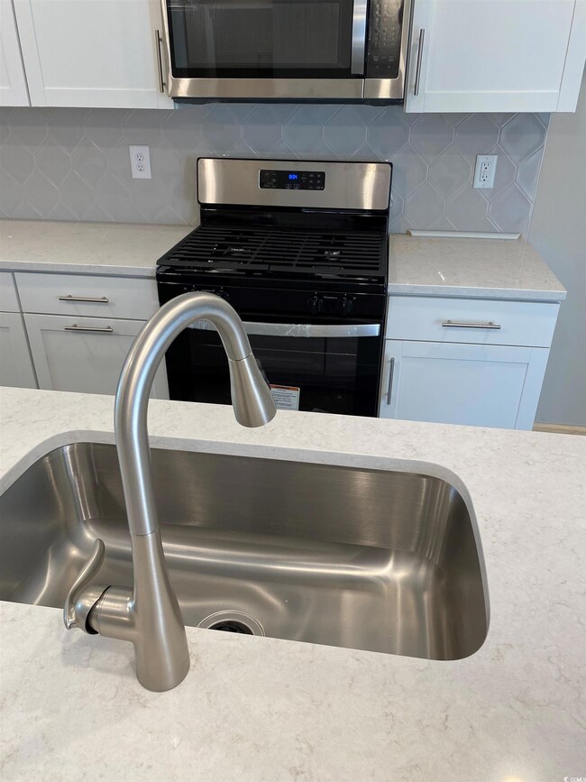Interior space featuring sink, backsplash, light s