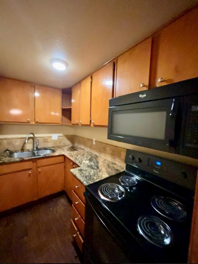 Kitchen featuring black appliances, open shelves, and dark wood finished floors