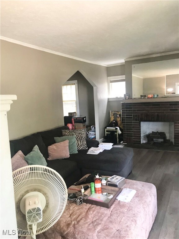 Living area featuring ornamental molding, a brick fireplace, and wood finished floors