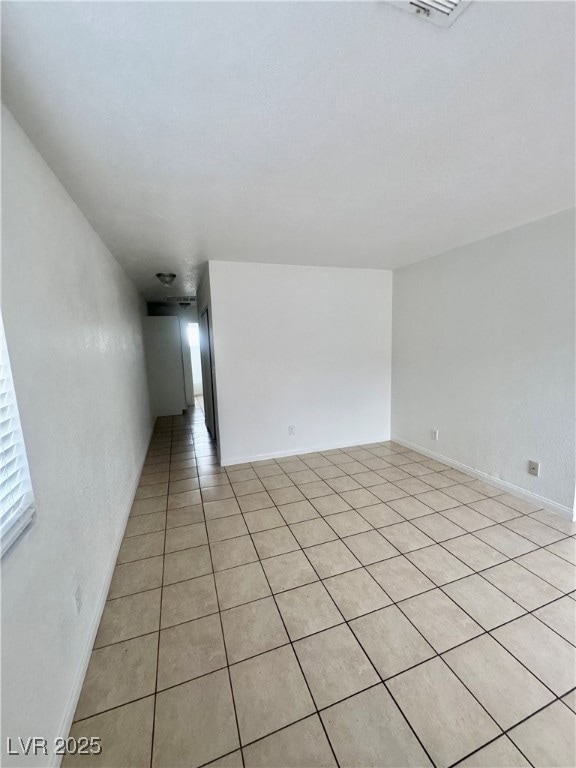 Empty room featuring light tile patterned flooring and a textured wall