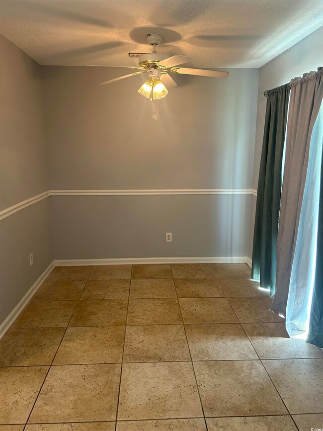 Tiled empty room with a textured ceiling and ceili