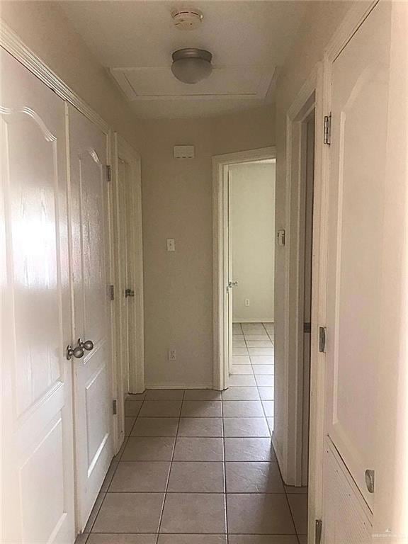 Hallway featuring light tile patterned floors and baseboards