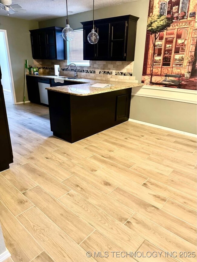 Kitchen with dark cabinets, a peninsula, light woo