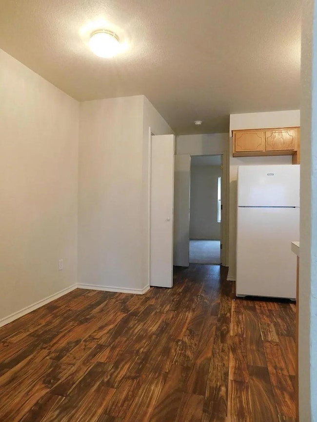 Kitchen featuring freestanding refrigerator, dark wood-style flooring, a textured ceiling, and light countertops