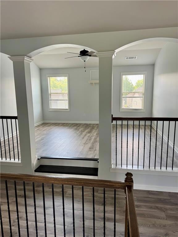 Staircase with wood finished floors, ceiling fan, healthy amount of natural light, and baseboards
