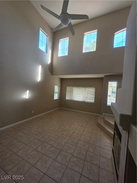 Unfurnished living room featuring a high ceiling, light tile patterned flooring, and ceiling fan