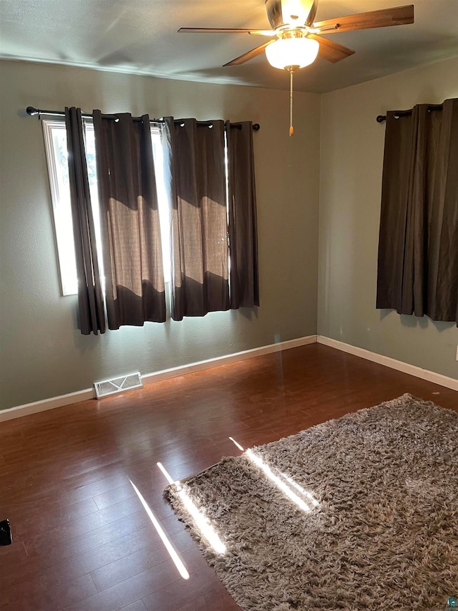 Empty room with ceiling fan and hardwood / wood-st